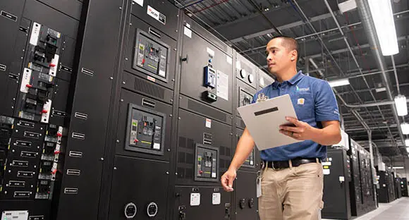 man walking in data center with clipboard